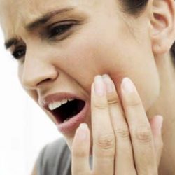 close-up of a young woman holding her cheek in pain